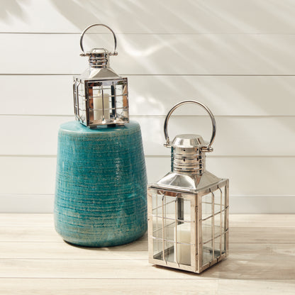 Two decorative lanterns beside a textured teal stool on a light wooden floor.