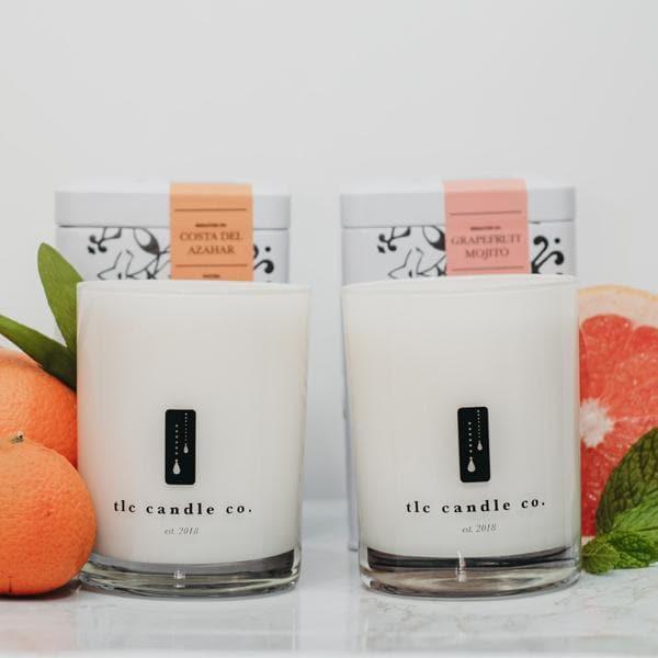 two white candles with grapefruits