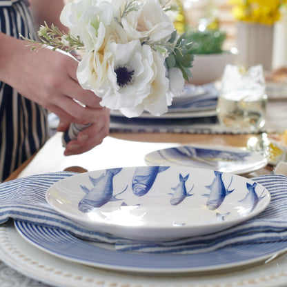 a table set with blue and white plates and flowers
