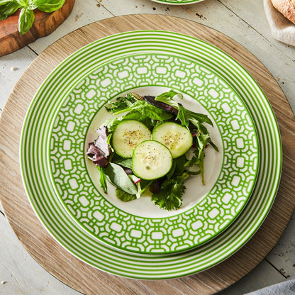 a green plate with cucumbers and greens on it