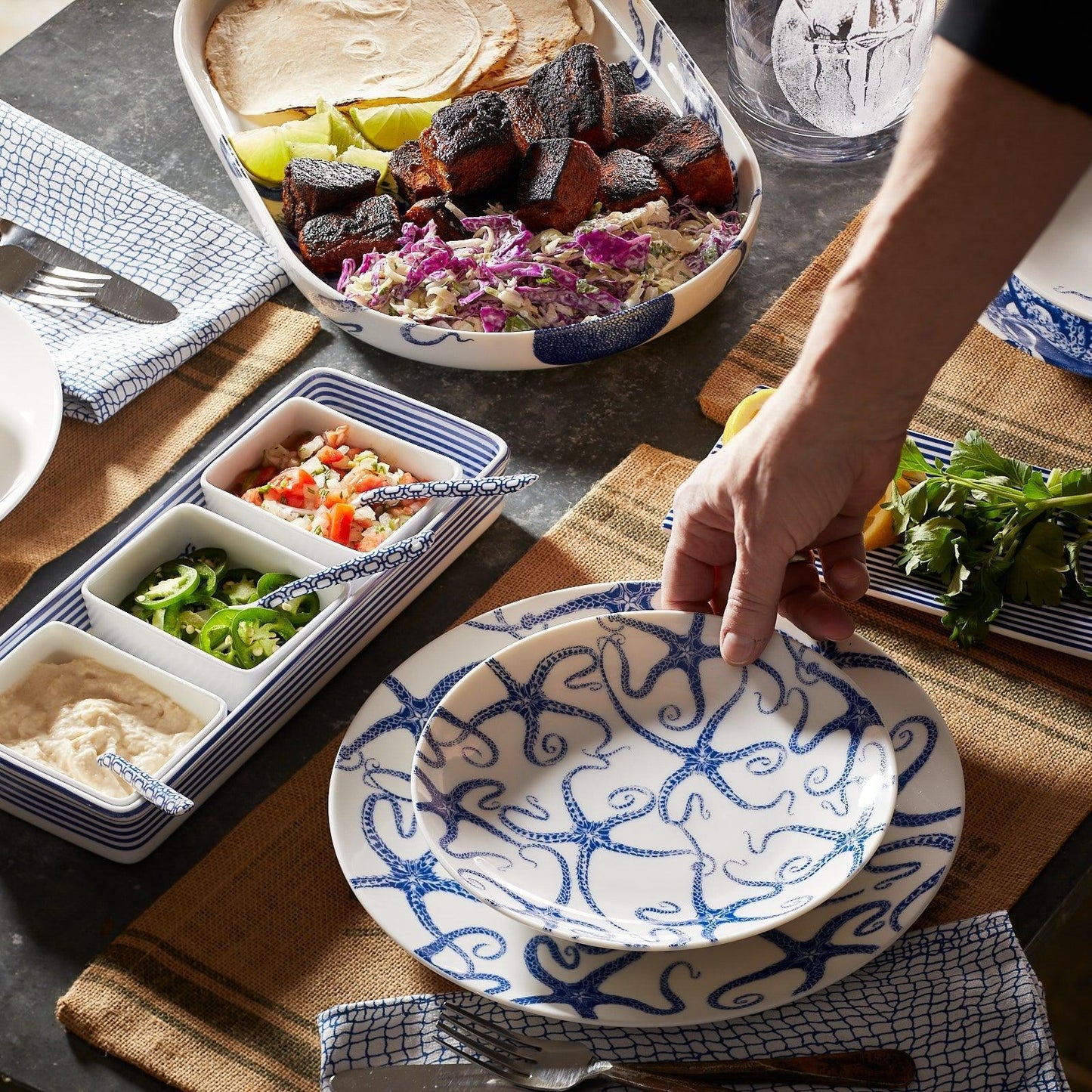 a person reaching for a plate of food on a table