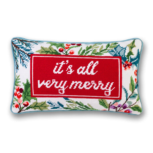 It’s All Very Merry needlepoint pillow with white lettering on red, a festive botanical border, and light blue piping