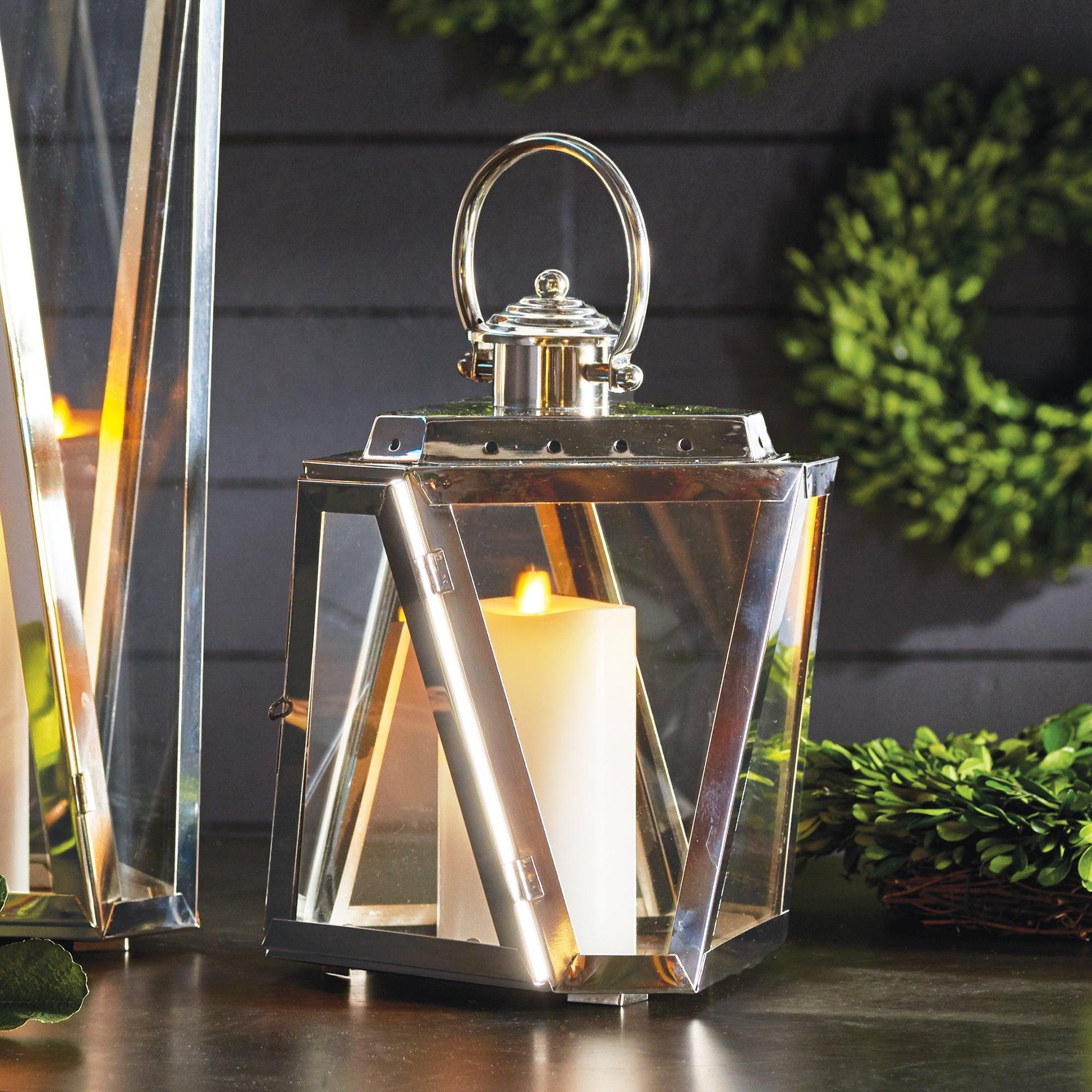 Silver candle lantern On a table in front of a wreath 