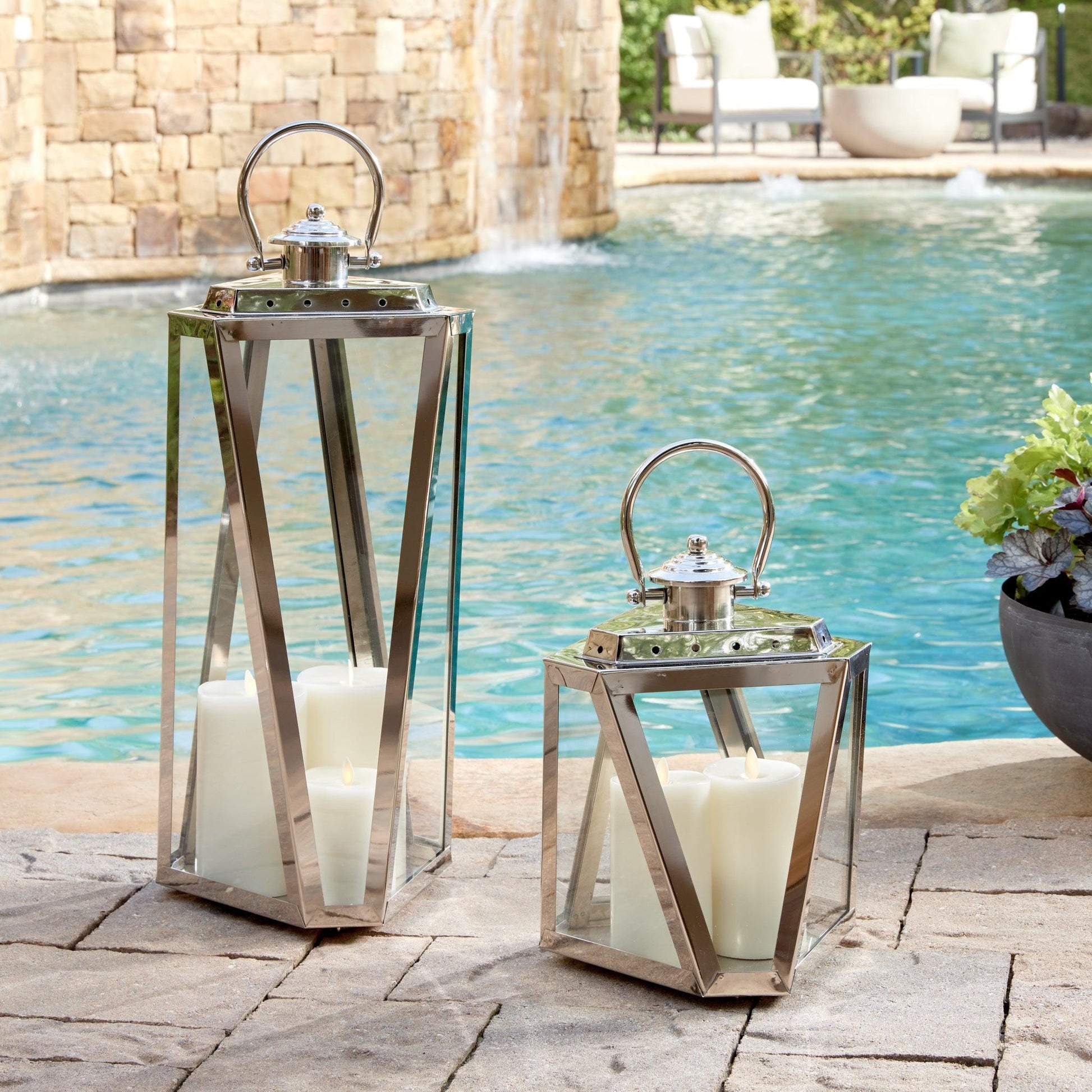 Two silver lanterns in front of a pool 