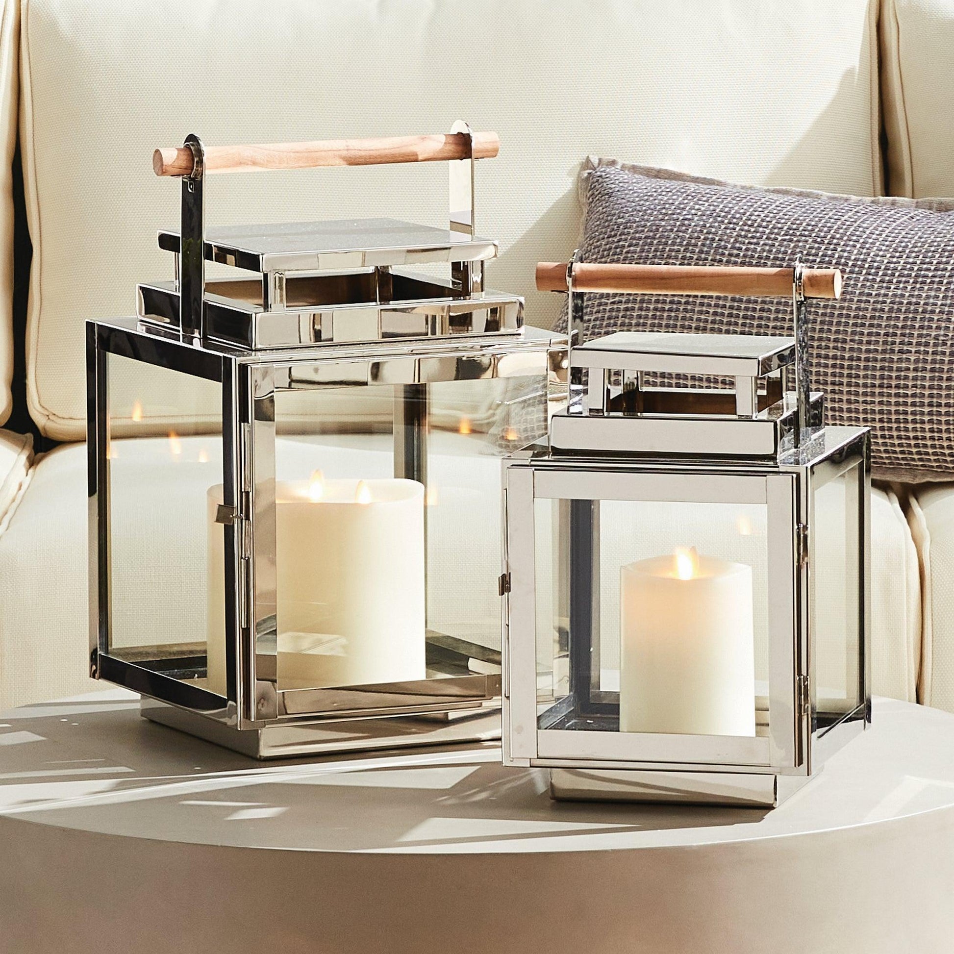 Two Silver lanterns with wood handles on a table 