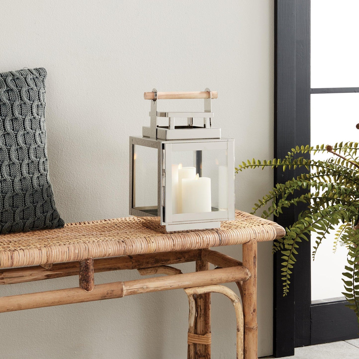 Silver lantern with wood handle on a rattan bench 