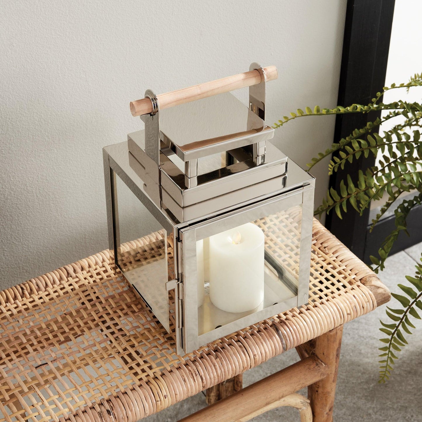 Silver lantern with wood handle on a rattan bench 