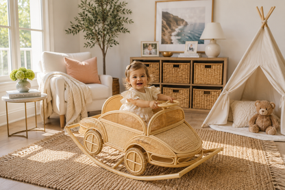 Child seated in a rattan rocking car in a neutral playroom beside a fabric teepee