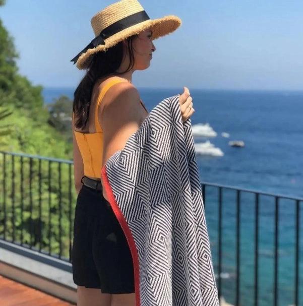 a woman with a hat and a towel on a balcony