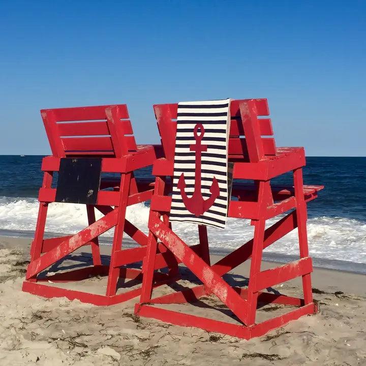 a couple of red chairs sitting on top of a sandy beach