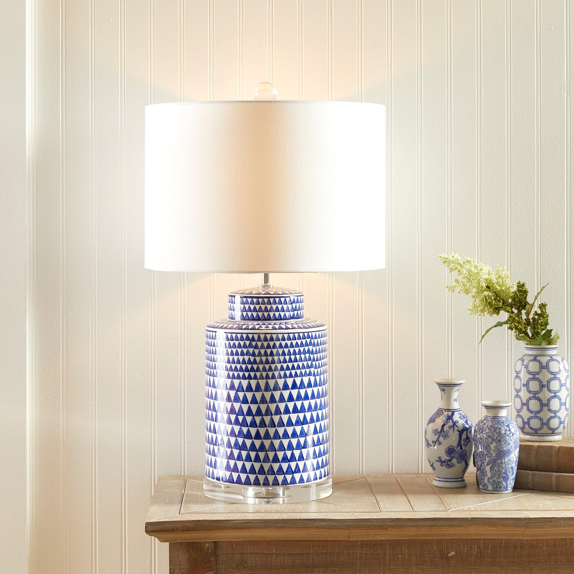 a blue and white vase sitting on a table next to a lamp