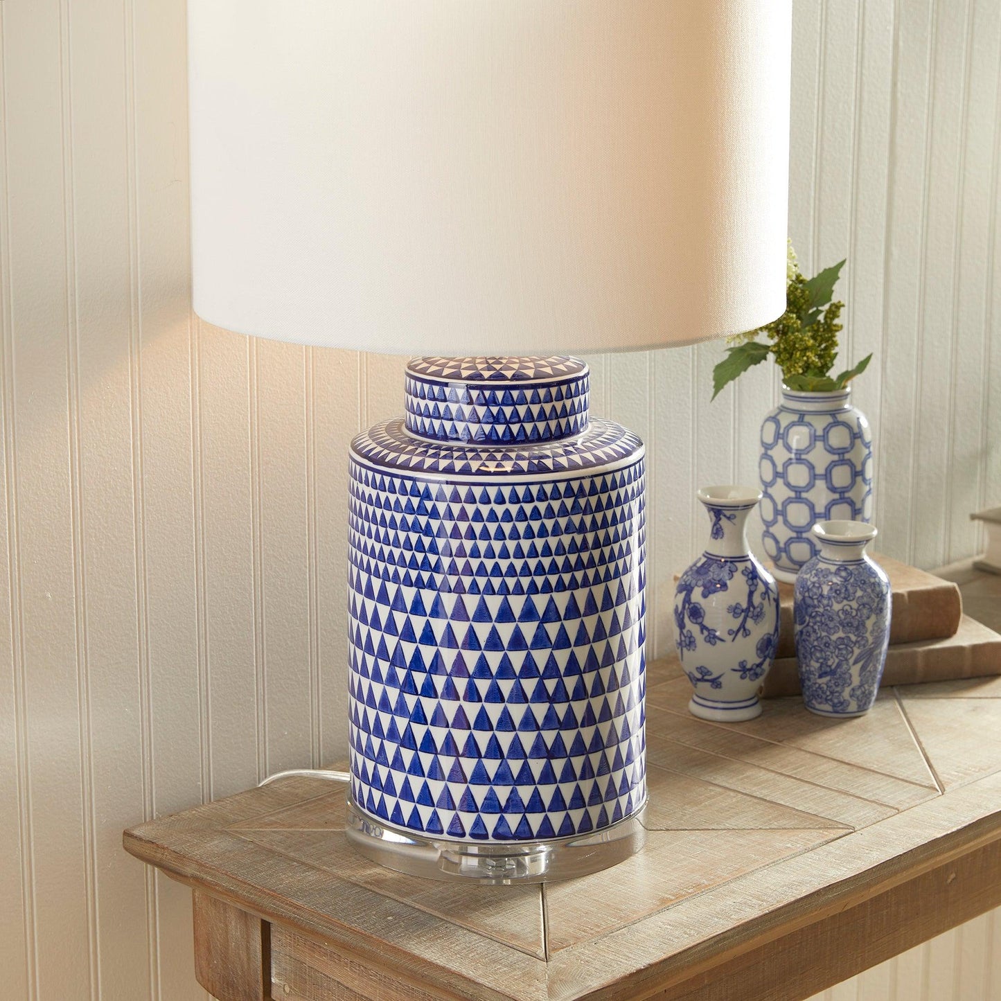 a blue and white vase sitting on a table next to a lamp