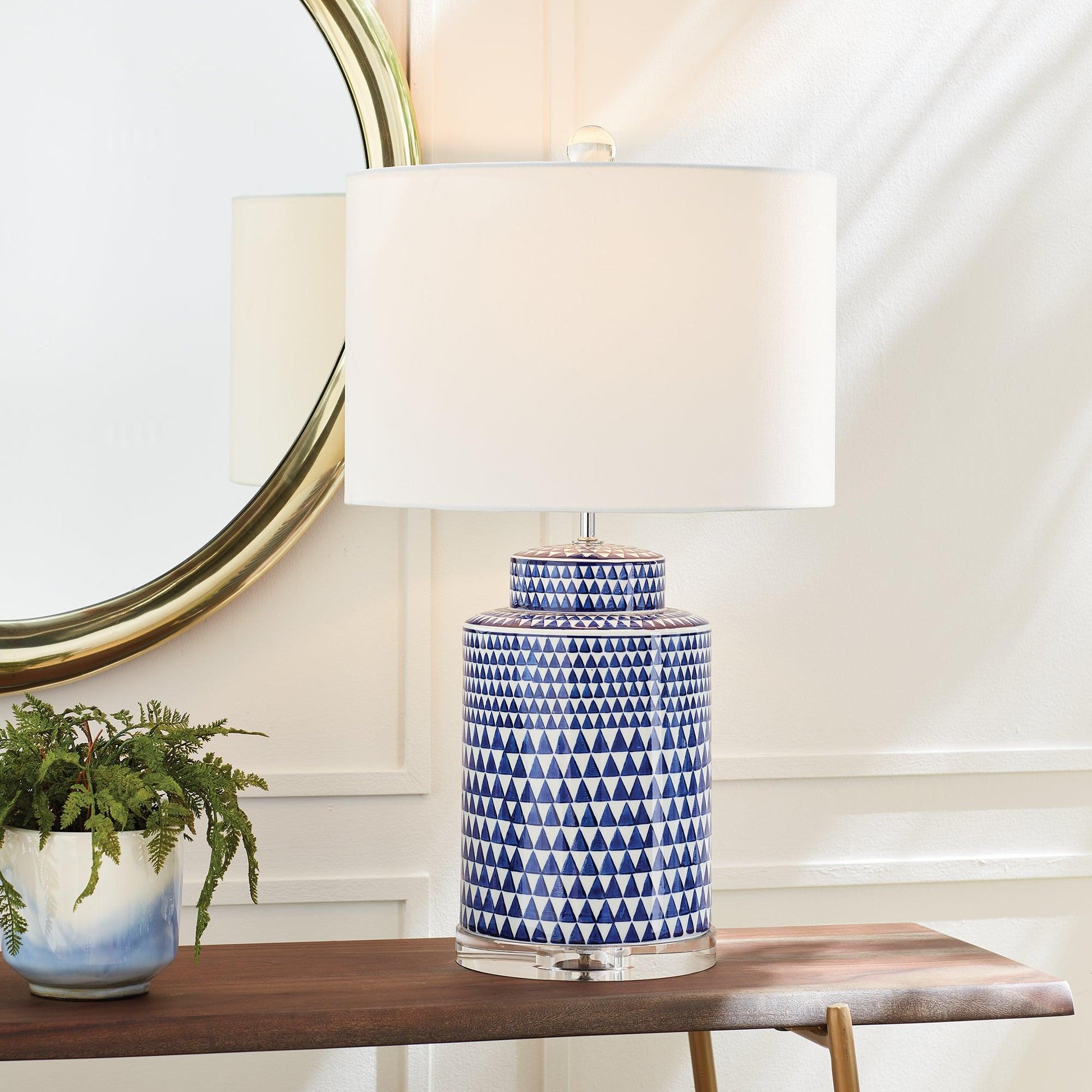 a blue and white vase sitting on a table next to a lamp