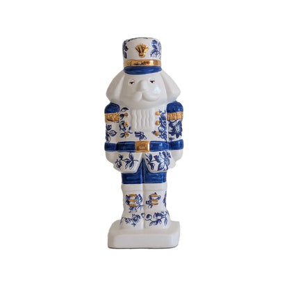 Front view of the blue and white toile Christmas nutcracker with gold accents on its hat, uniform, and boots