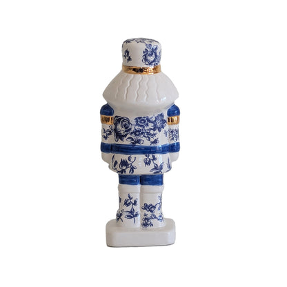 Rear view of the blue and white toile nutcracker showing patterned uniform details and gold trim