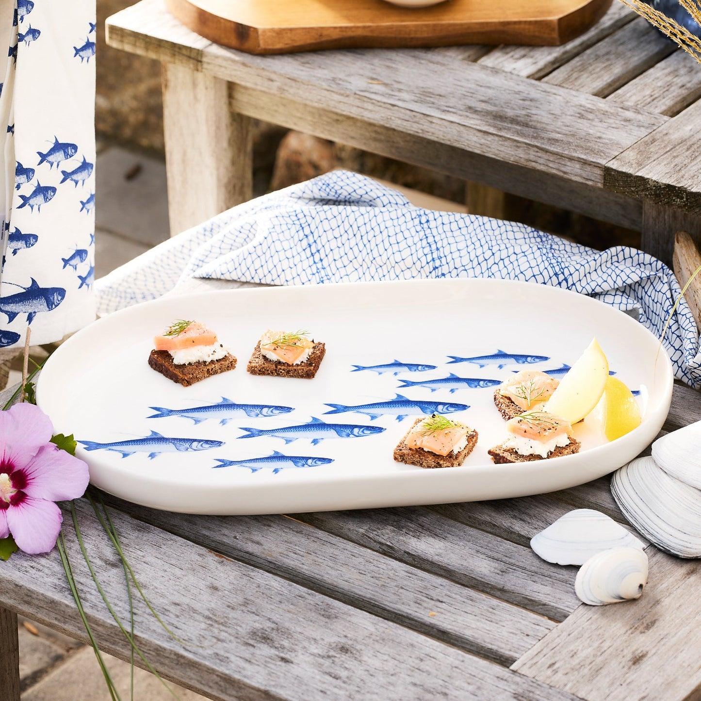 white platter with blue fish on a wooden bench