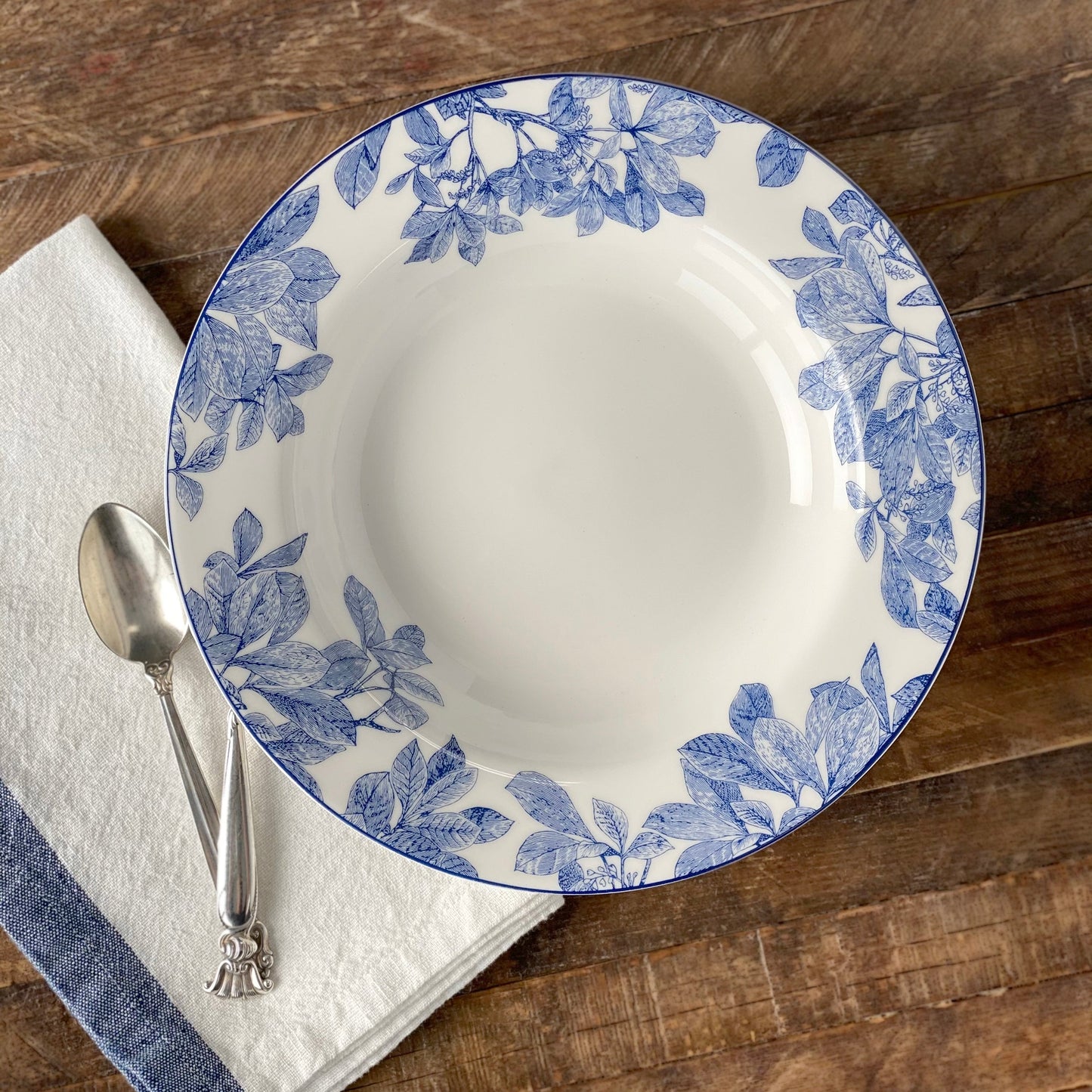 wood table with blue and white bowl and napkin with silver spoon