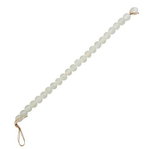 a white beaded decoration with a twine clasp