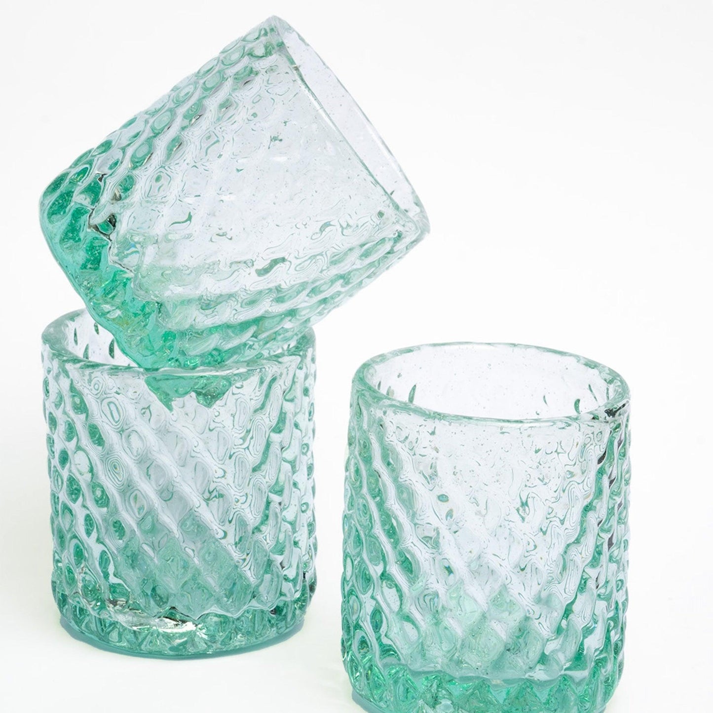 a set of three green glass tumblers sitting next to each other