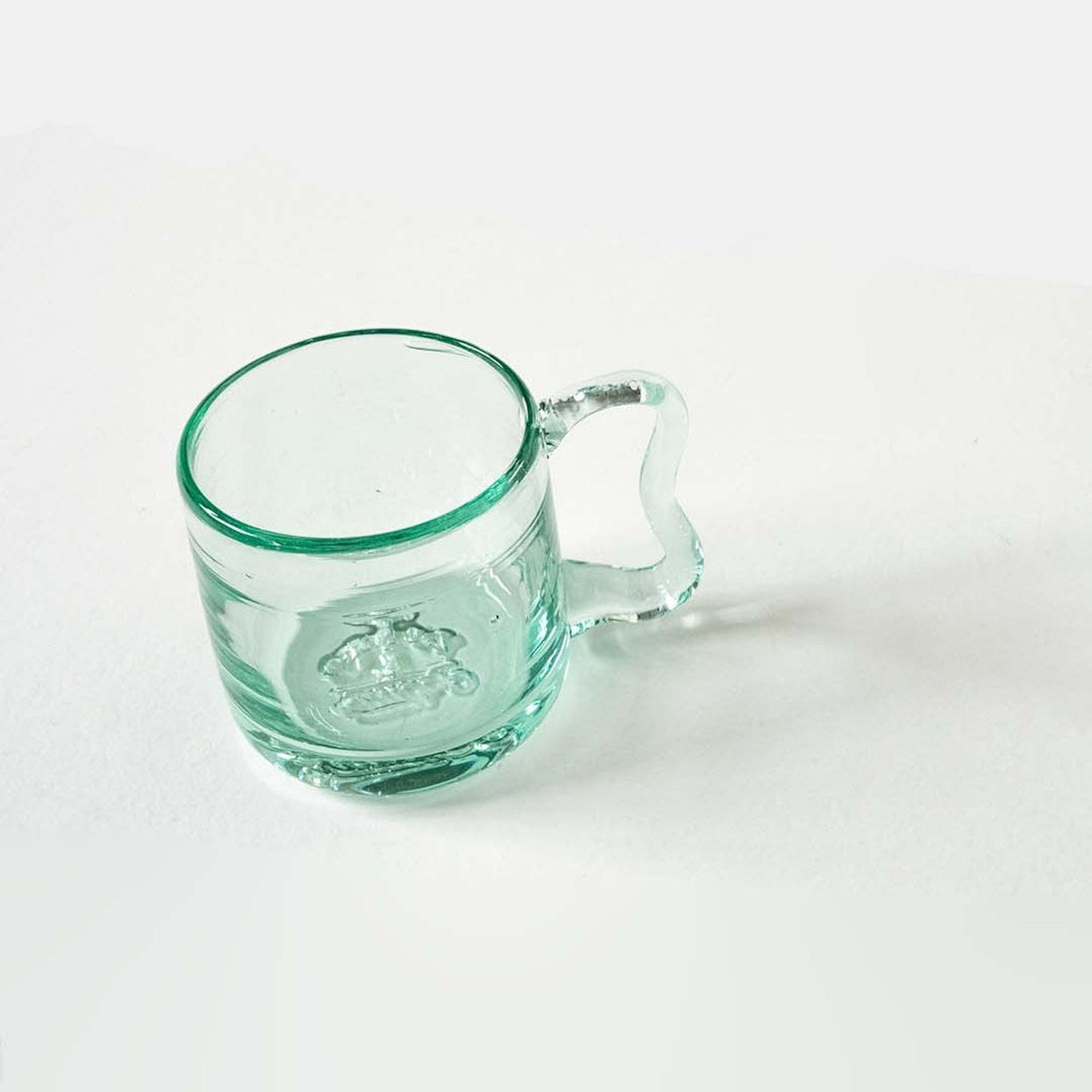 a glass cup with a handle on a white surface