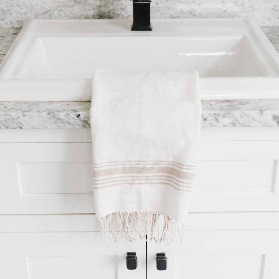 white and beige hand towel on a kitchen sink