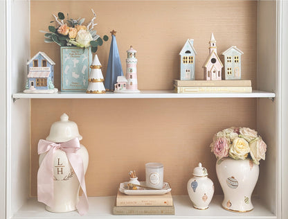 Holiday bookshelf display featuring a Serenity Blue folded Christmas tree among miniature houses, flowers, and decorative jars