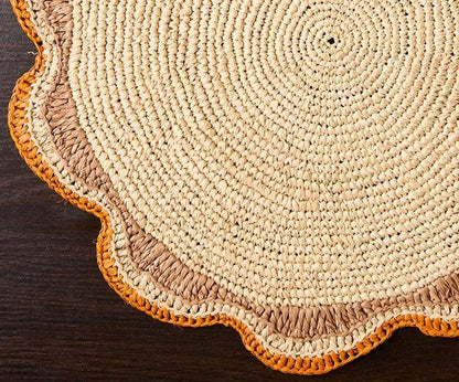 Round woven mat with a scalloped edge, featuring natural and orange-brown tones.