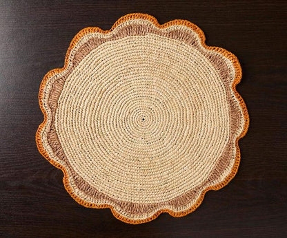 Round braided rug with a scalloped edge, featuring beige and orange colors on a dark surface.