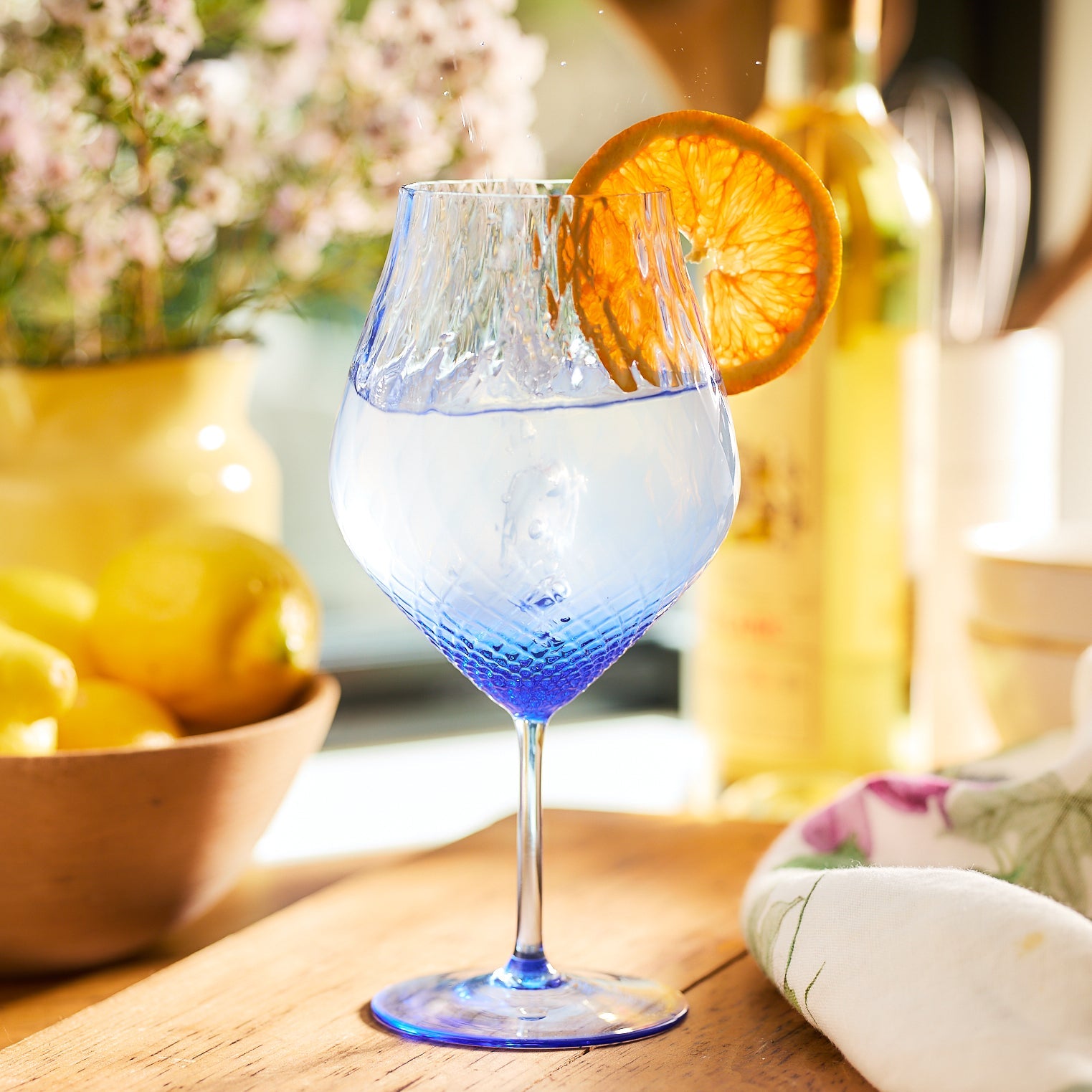 blue wine glass with a lemon on a wood table