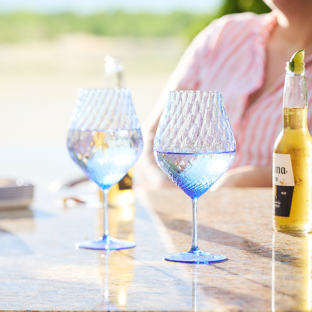 two blue wine glasses next to a beer