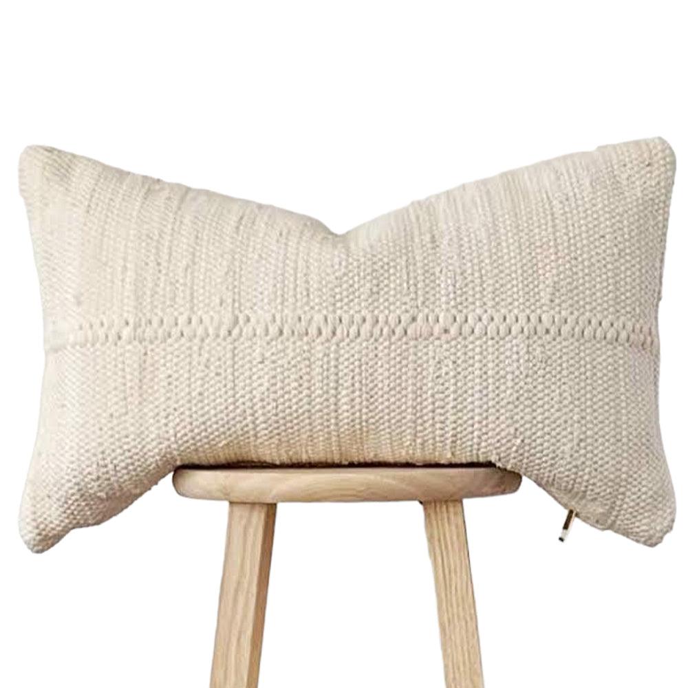 a white pillow sitting on top of a wooden stool