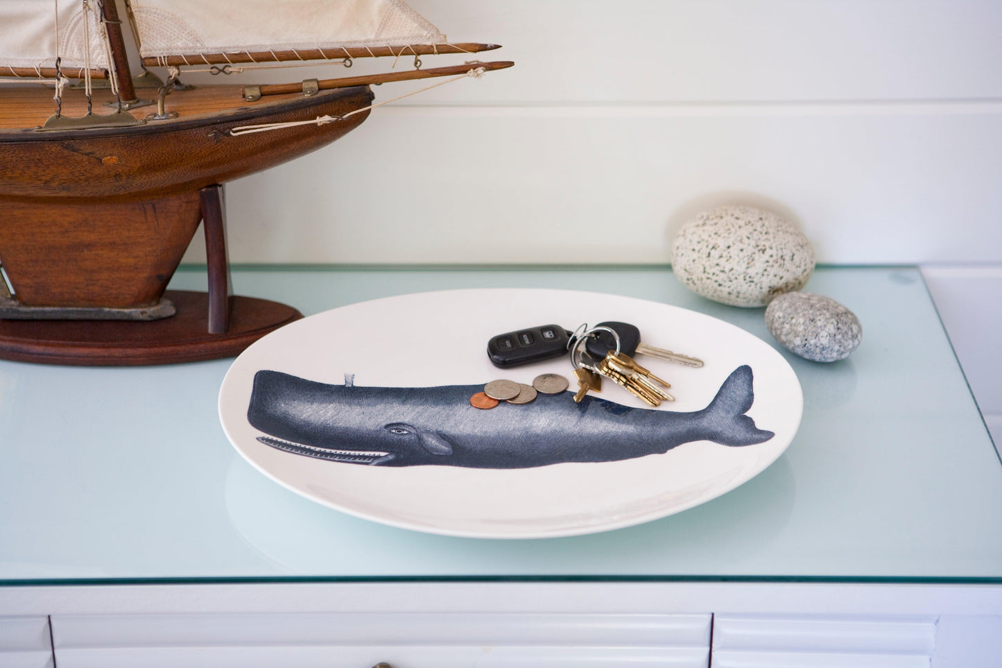 white tray with blue whale on a table with keys and a boat