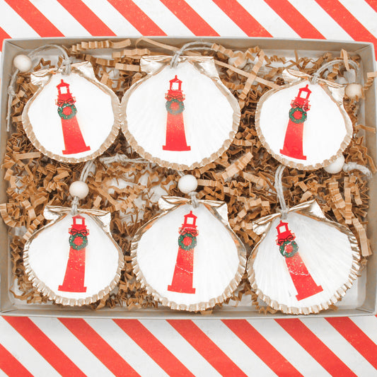 set of six shell ornaments with red christmas lighthouses on a red and white striped background