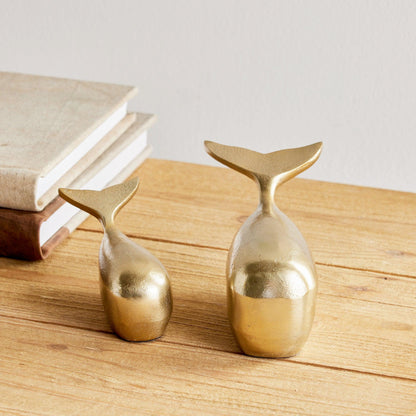 a couple of gold whales sitting on top of a wooden table