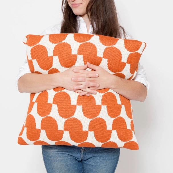 a woman holding a large orange and white pillow