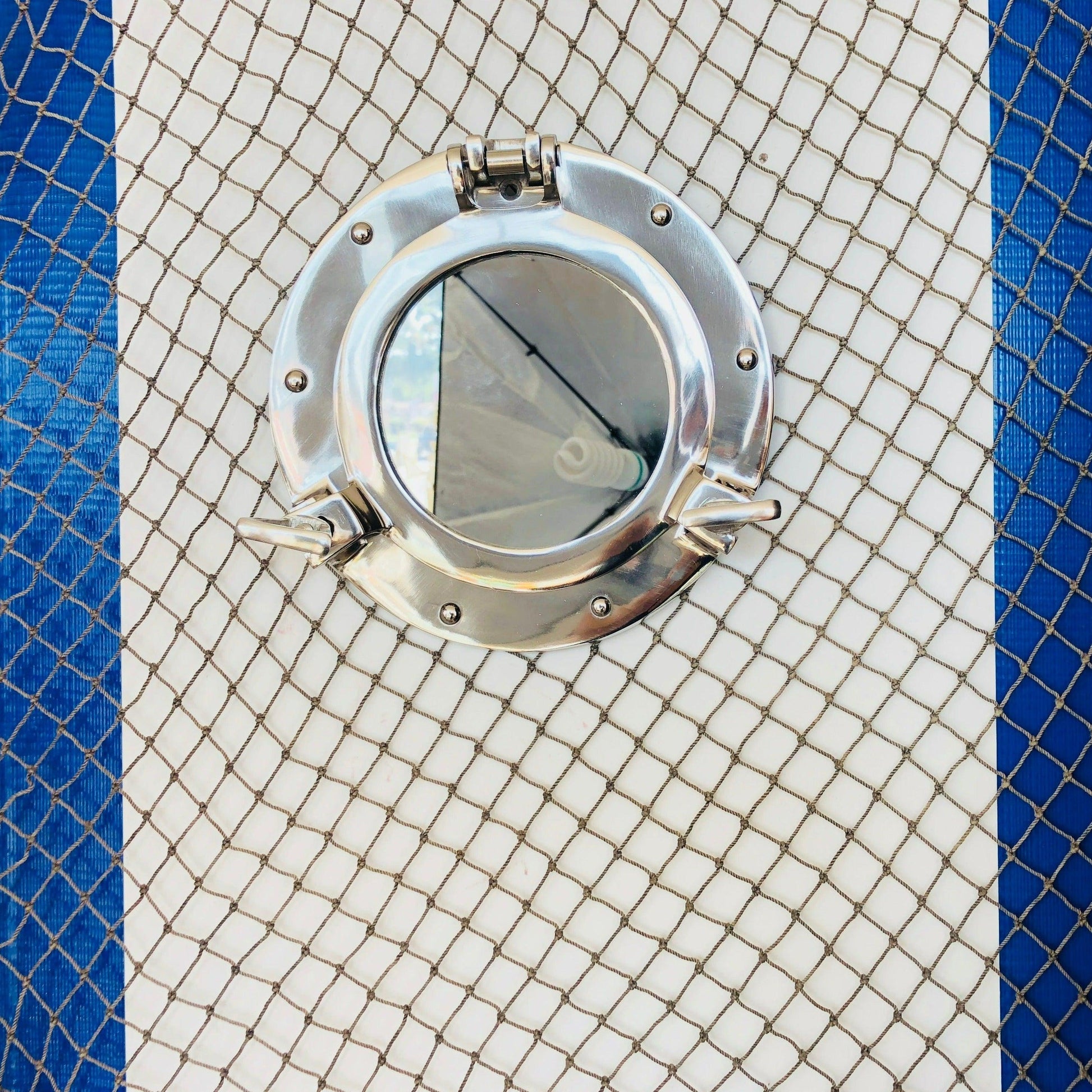 a close up of a metal porthole on a blue and white wall