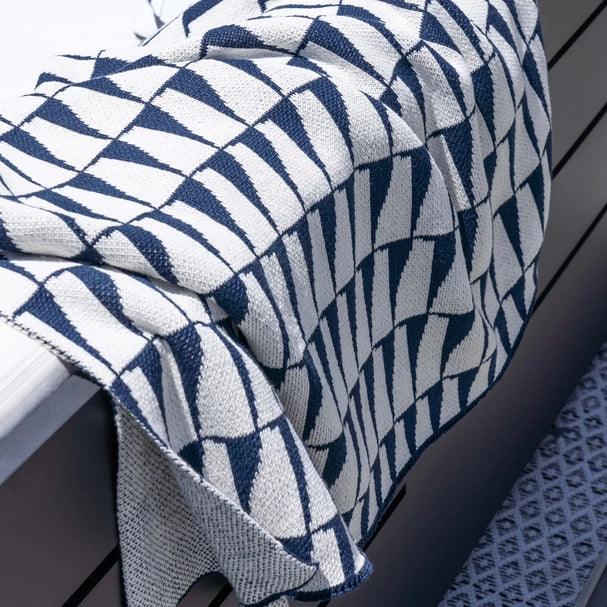 a blue and white blanket sitting on top of a bench