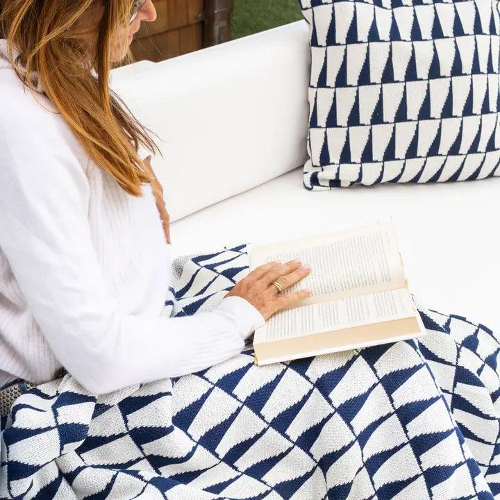 a woman sitting on a couch reading a book