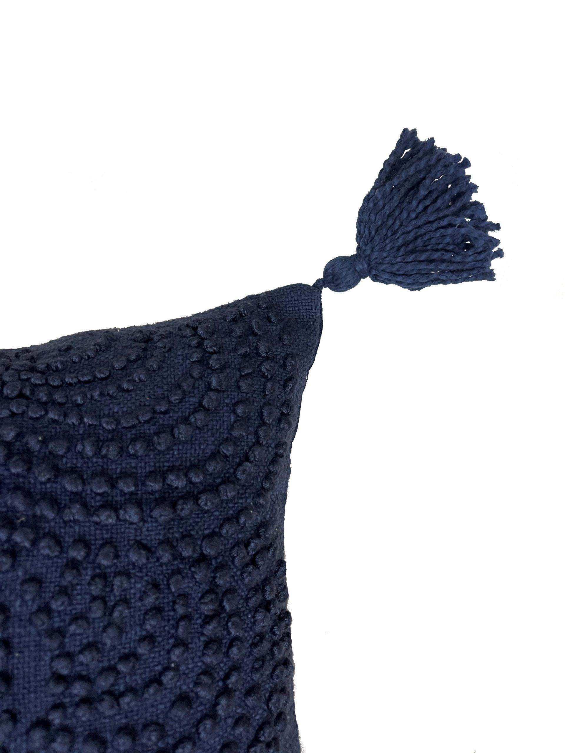 close up of corner of dark blue pillow with tassel