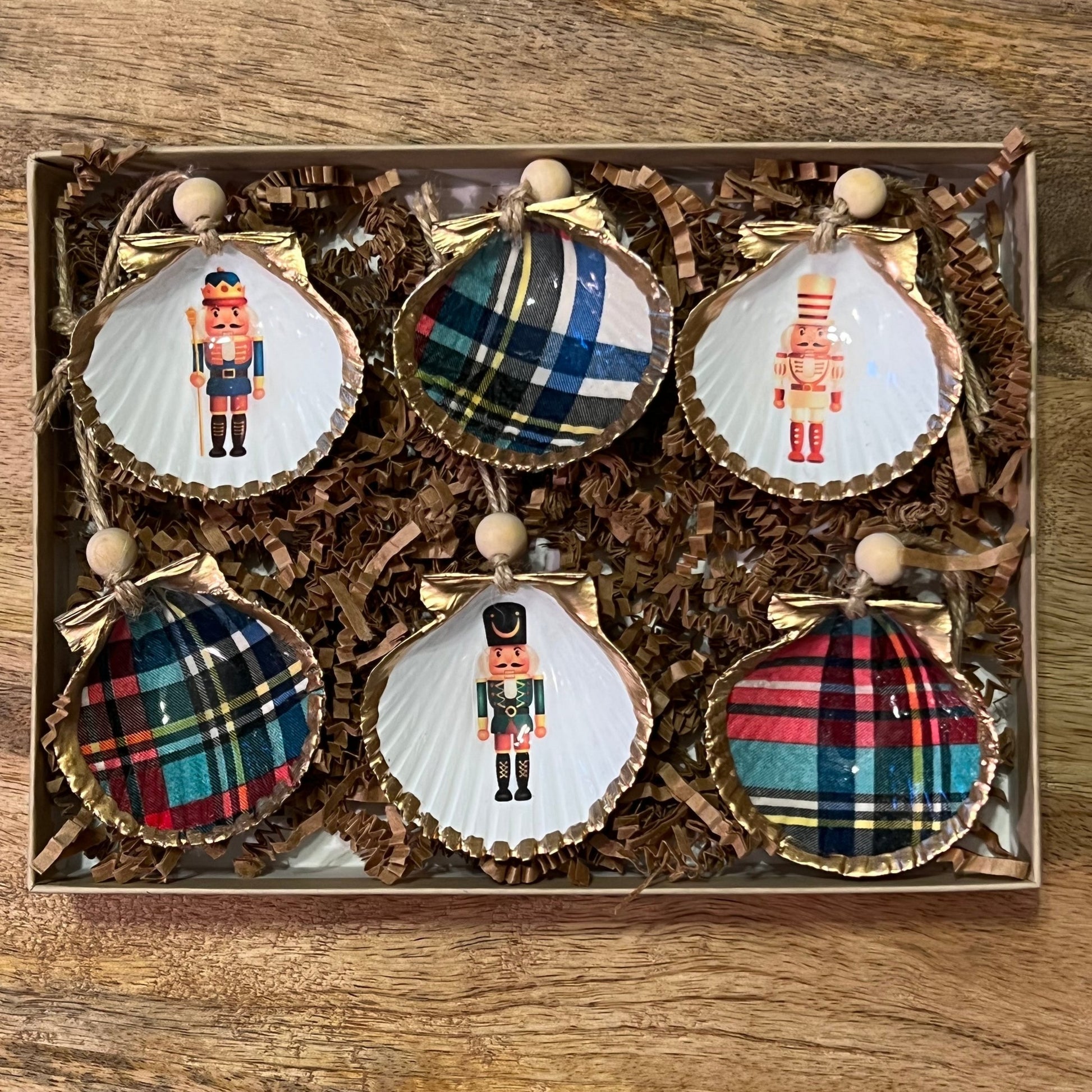 set of six shell ornaments painted with plaid designs and nutcrackers