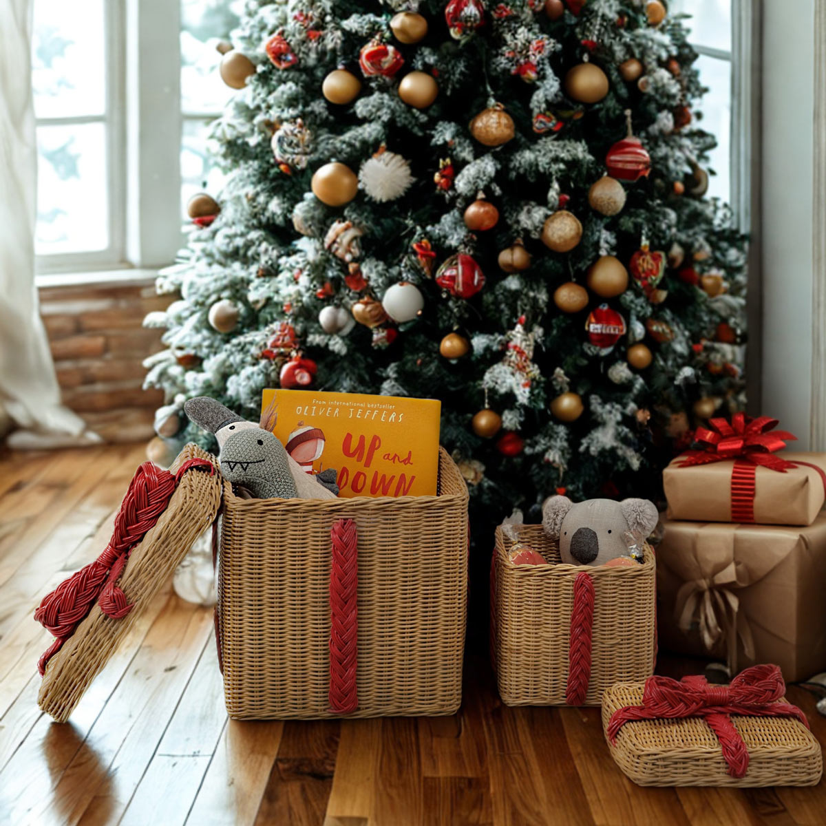 	Two open rattan gift boxes holding books and stuffed toys beside a Christmas tree