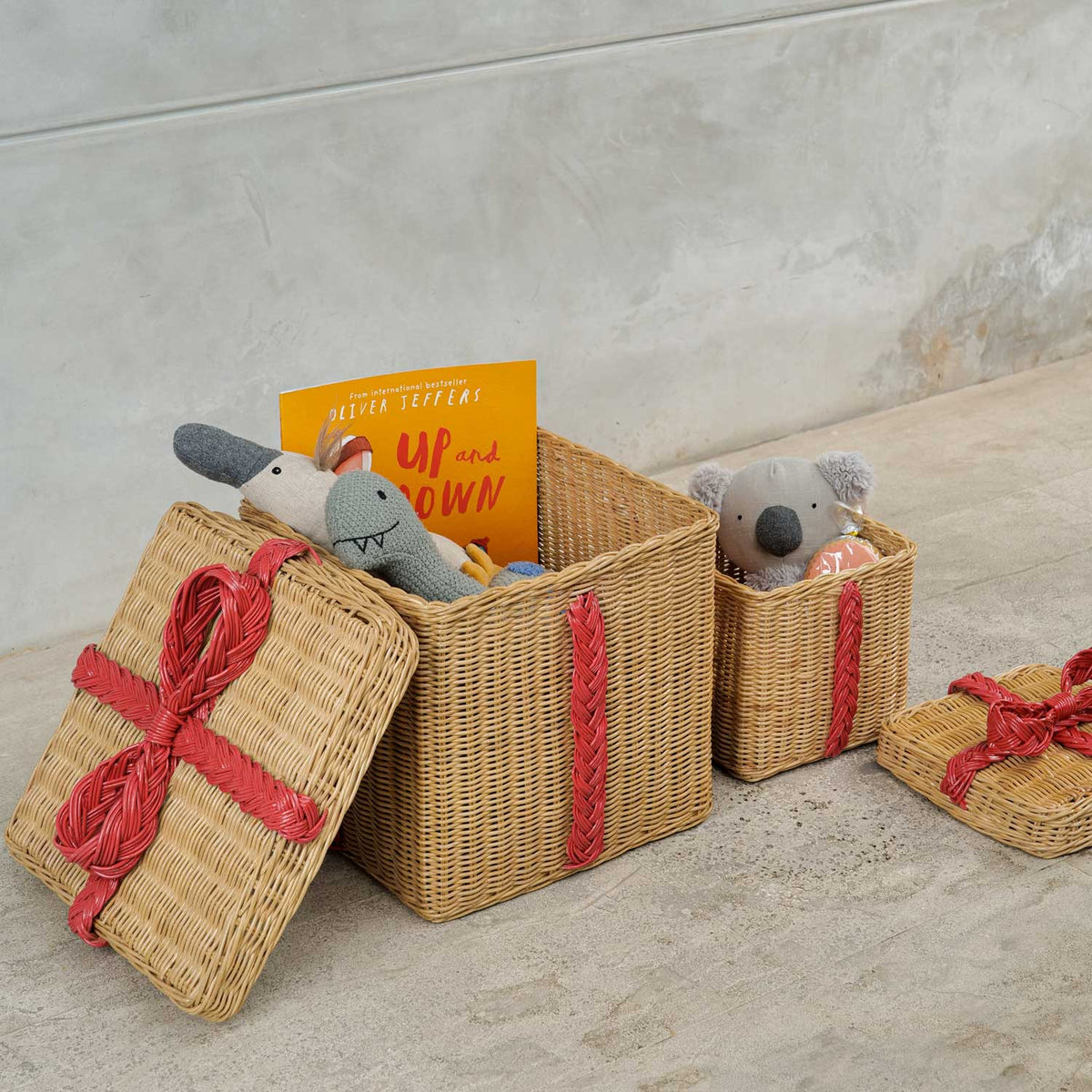 	Large and small open rattan storage gift boxes filled with toys and a book, with lids alongside