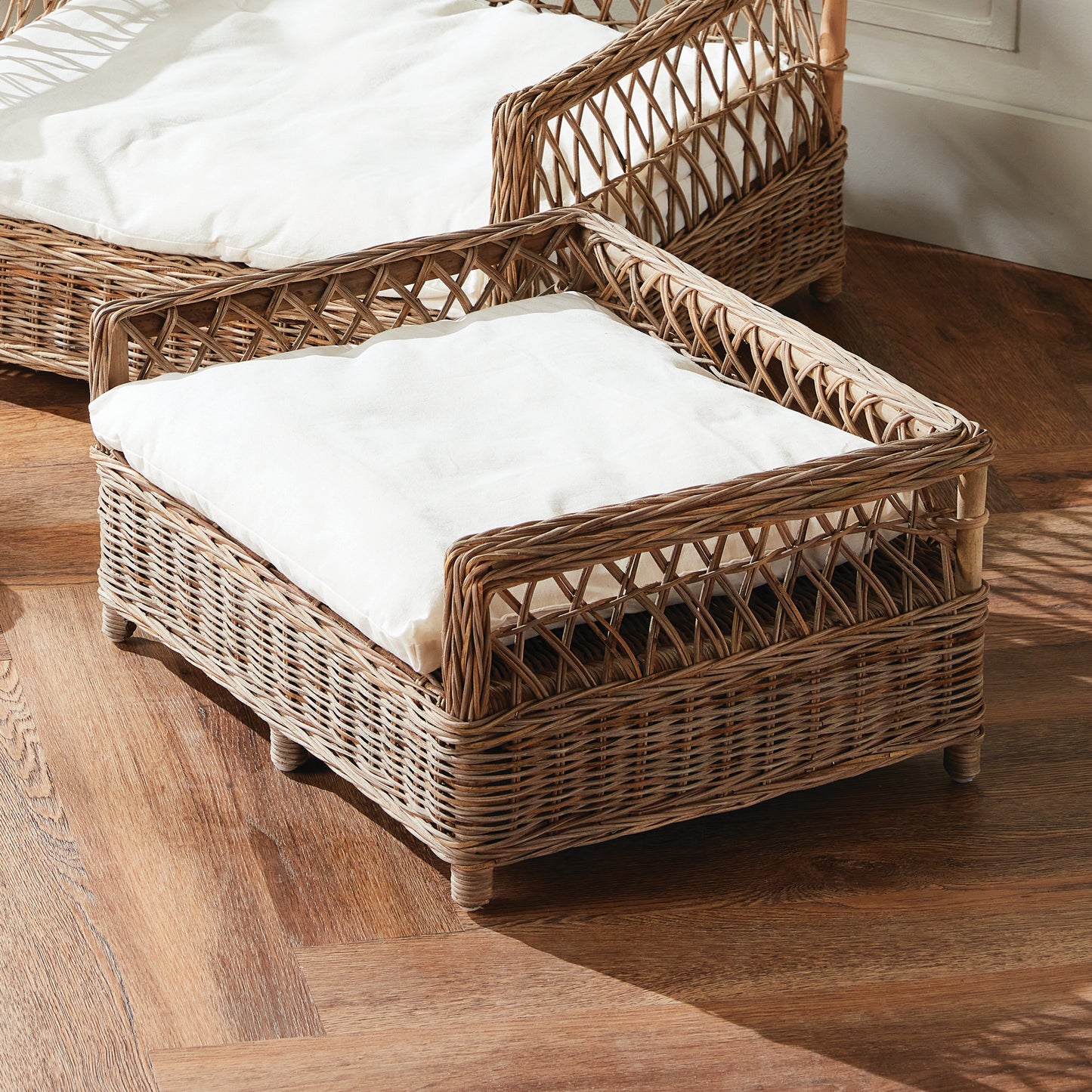 two rattan dog beds with white cushions