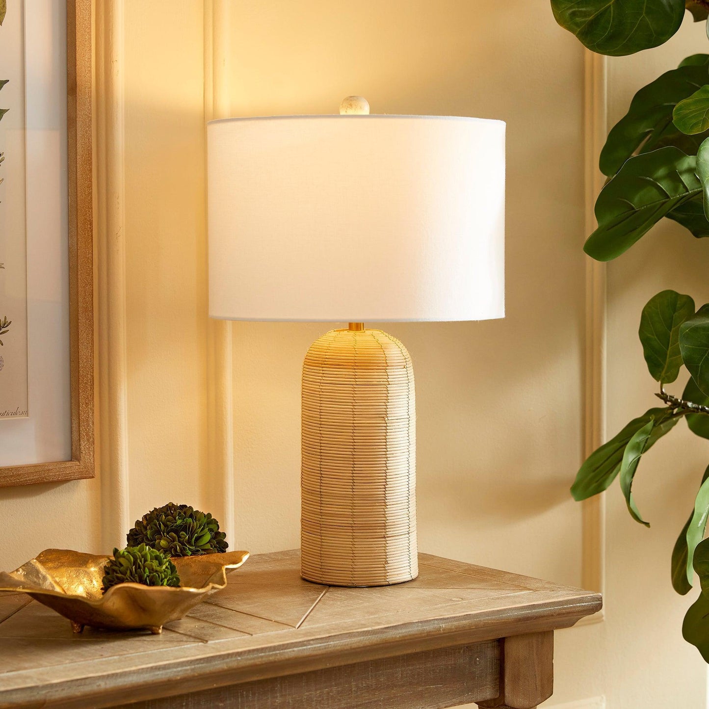 a rattan lamp on a wood table next to a gold bowl