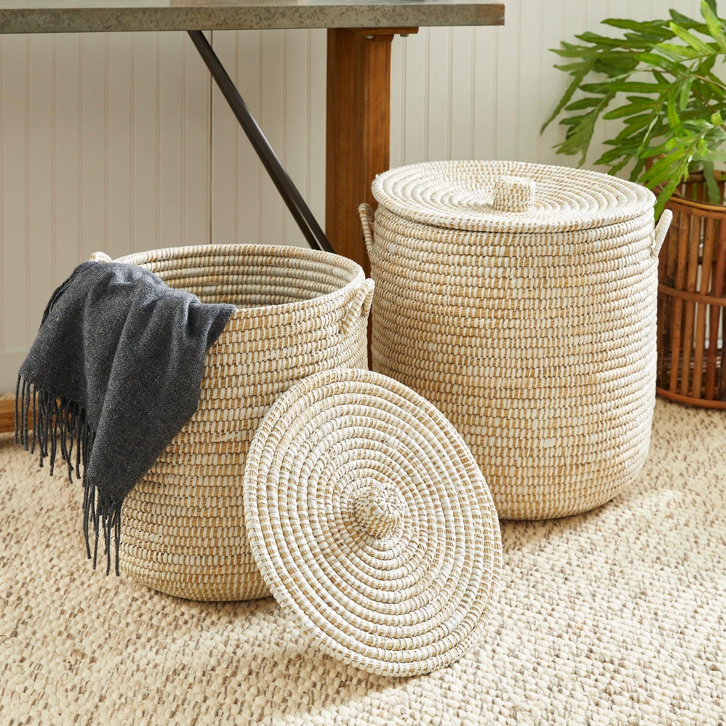 two woven baskets sitting on top of a rug next to a wooden table