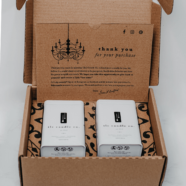 two white candles in a brown box