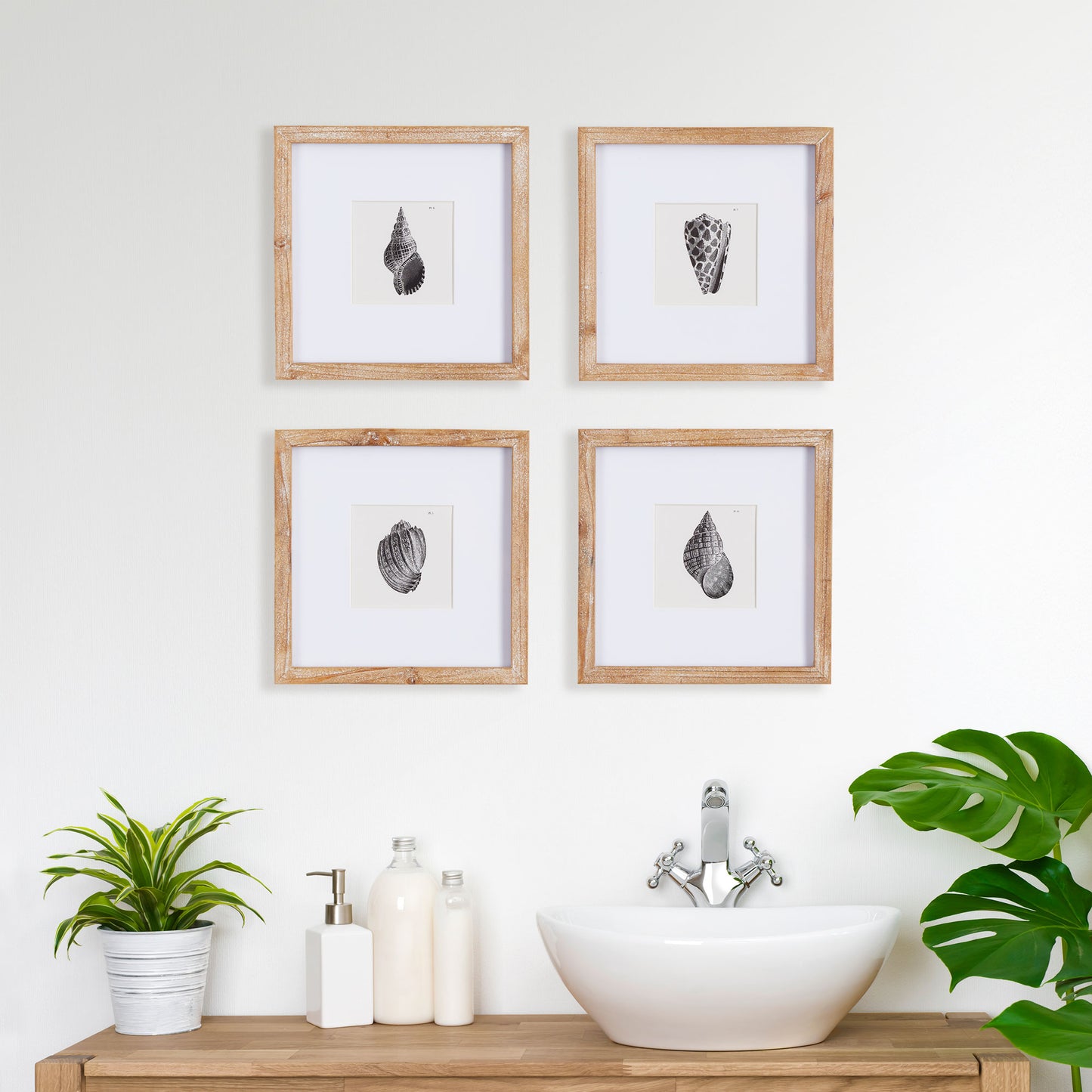 four black and white shell art prints on a bathroom wall