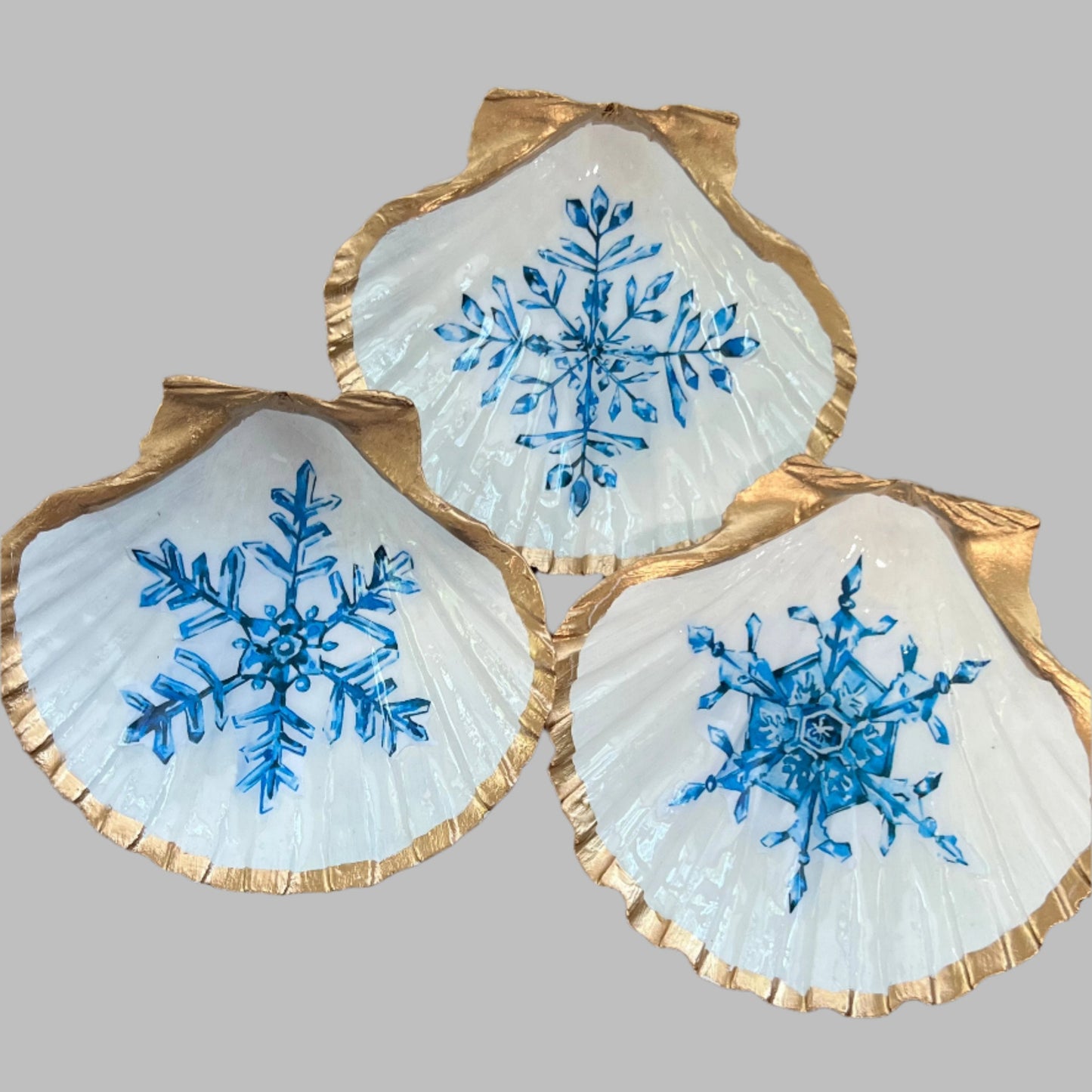 three shells painted white with blue snowflakes