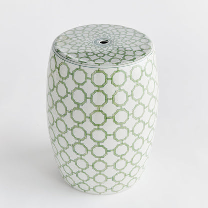 a green and white vase sitting on top of a white table