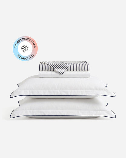 Porto cooling sheet set with folded sheets, two blue-trimmed white pillowcases, and a temperature-regulating badge